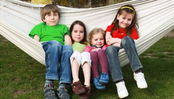 Vier Kinder sitzen zusammen in einer Hängematte | © eyezoom100 - Fotolia